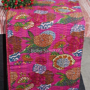 May include: A pink kantha quilt with a floral pattern in shades of brown, green, and blue. The quilt is made of cotton and has a hand-stitched design.