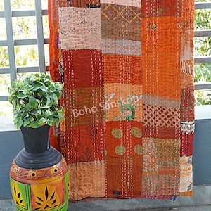 Puede incluir: Una colcha de retazos con una variedad de telas de color naranja, marrón y crema. La colcha está cosida a mano y tiene un estilo rústico y bohemio.