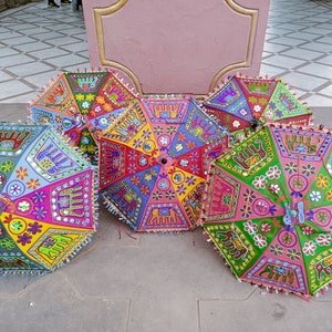 Puede incluir: Una colecci&oacute;n de cinco paraguas coloridos con bordados e incrustaciones intrincados. Los paraguas est&aacute;n hechos de tela y tienen una variedad de patrones, incluyendo dise&ntilde;os florales, formas geom&eacute;tricas y motivos de animales. Los paraguas est&aacute;n dispuestos en semic&iacute;rculo sobre un suelo de baldosas.