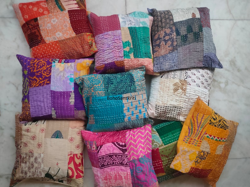 May include: A collection of ten colorful patchwork throw pillows with various patterns and textures. The pillows are made from recycled saris and are perfect for adding a touch of bohemian style to any room.