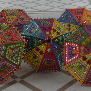 Puede incluir: Cinco paraguas coloridos con bordados intrincados y adornos de espejo. Los paraguas est&aacute;n hechos de tela y tienen un dise&ntilde;o tradicional indio.