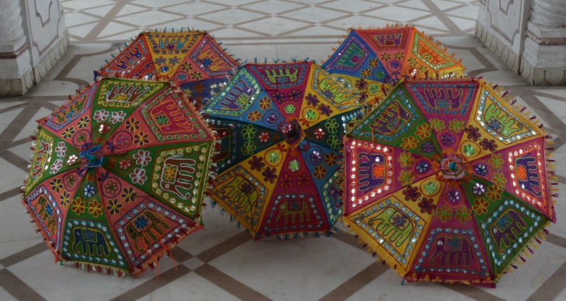 Puede incluir: Cinco paraguas coloridos con bordados intrincados y adornos de espejo. Los paraguas est&aacute;n hechos de tela y tienen un dise&ntilde;o tradicional indio.