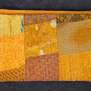 May include: A patchwork quilt made of various shades of yellow and orange fabric. The quilt is hand-stitched and has a unique, rustic look. "Boho Sanskriti" is printed on the quilt.
