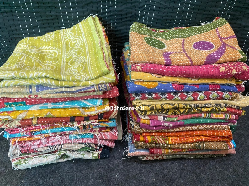 May include: Two stacks of colourful kantha quilts, each with a different pattern. The quilts are made from recycled saris and are hand-stitched. The top quilt in each stack has a light green and white pattern, while the bottom quilt in each stack has a dark brown and orange pattern. @BohoSanskruti