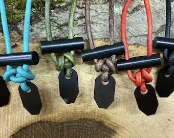 May include: Seven different colored paracord necklaces with black fire starter sticks and black metal pendants. The necklaces are displayed on a wooden surface.