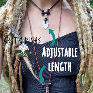 May include: Two necklaces with adjustable length. The top necklace is black with a white arrowhead pendant. The bottom necklace is brown with a black pendant. The text "ADJUSTABLE LENGTH" is in white.