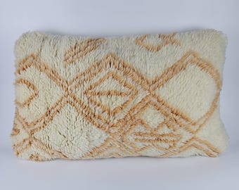 May include: A white and beige rectangular pillow with a geometric pattern. The pillow is made of a soft, fluffy material.
