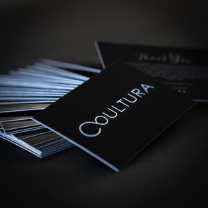 May include: A stack of black business cards with the word "CULTURA" printed in white on the top card.