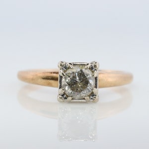 May include: A gold ring with a square-shaped diamond set in a white gold setting.