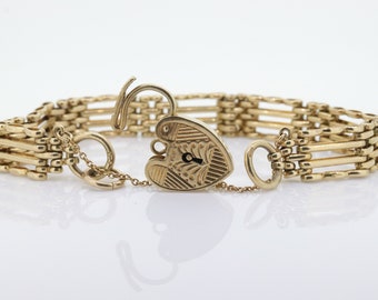May include: A gold chain bracelet with a heart-shaped padlock clasp. The bracelet is made of multiple strands of chain and has a delicate design.