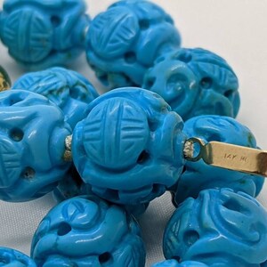 May include: A turquoise blue carved bead necklace with a gold clasp marked "14K W".
