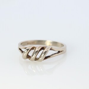 Könnte beinhalten: Ein silberner Ring mit einem gedrehten Design. Der Ring ist schlicht und elegant.