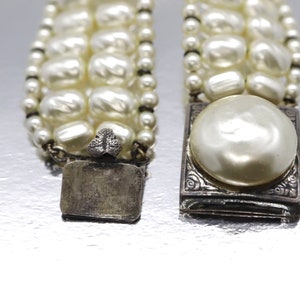 May include: A multi-strand pearl bracelet with silver clasps. The clasps have a floral design and one has a large pearl in the center.
