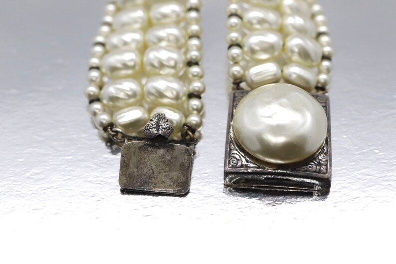 May include: A multi-strand pearl bracelet with silver clasps. The clasps have a floral design and one has a large pearl in the center.