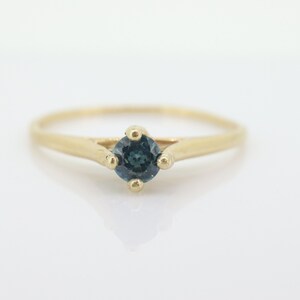 May include: A gold ring with a single, round, dark blue gemstone set in the center.