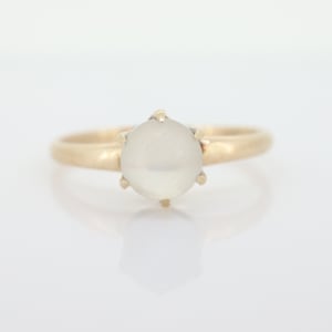 Könnte beinhalten: Ein goldener Ring mit einem weißen Mondstein als Mittelstück.