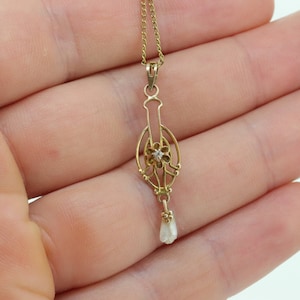 May include: A gold pendant necklace with a delicate floral design and a single pearl drop. The pendant features a small diamond in the center of the flower.