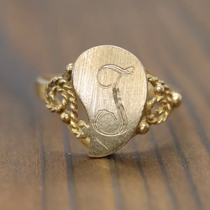 Anel de sinete com letra I ou J. Ouro amarelo 14k com meio coração. Letra gravada I ou J