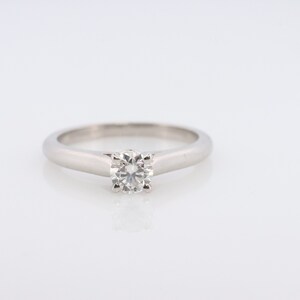 May include: A silver solitaire engagement ring with a round brilliant cut diamond