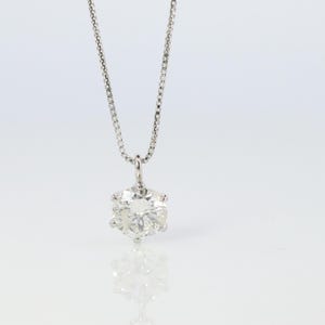 May include: A silver chain necklace with a large, clear, round diamond pendant.