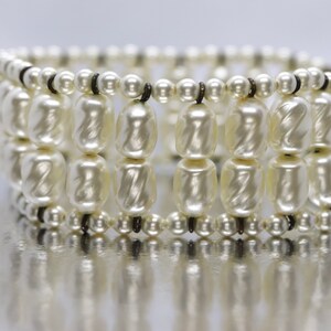 May include: A white pearl bracelet with multiple rows of pearls and a black clasp.