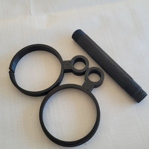 May include: A black plastic pipe fitting with two circular rings and a threaded end.