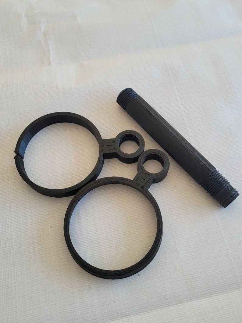 May include: A black plastic pipe fitting with two circular rings and a threaded end.