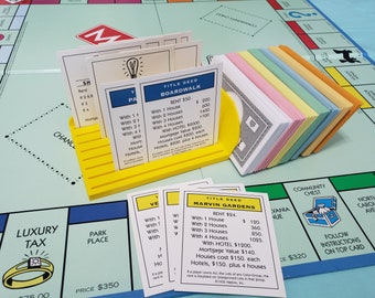 Puede incluir: Primer plano de un tablero de juego de Monopoly con cartas de propiedad para Boardwalk, Marvin Gardens y Park Place. Las cartas son de color amarillo, blanco y azul claro, respectivamente. Las cartas tienen el nombre de la propiedad, el alquiler y los costes de las casas y los hoteles impresos en ellas.