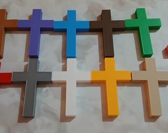 Może przedstawiać: Kolekcja jedenastu drewnianych krzyży w różnych kolorach, w tym brązowym, fioletowym, niebieskim, zielonym, czerwonym, szarym, białym, żółtym i beżowym. Krzyże ułożone są w siatkę, z jednym krzyżem lekko przesuniętym.