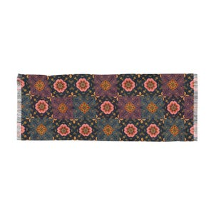 May include: A rectangular scarf with a repeating floral pattern. The design features pink flowers, purple squares, and gold accents on a navy blue background. The scarf has fringed edges.