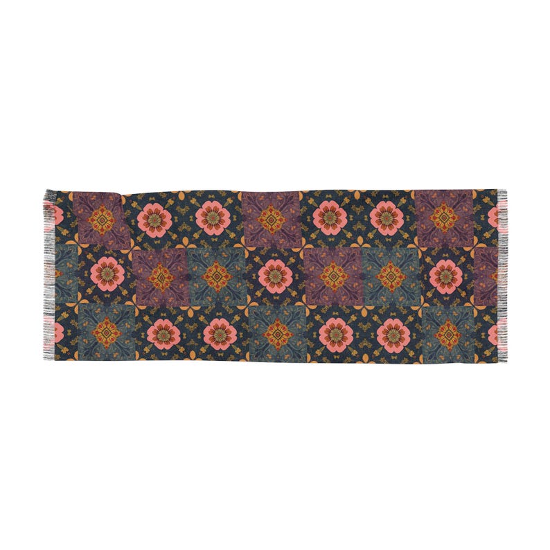 May include: A rectangular scarf with a repeating floral pattern. The design features pink flowers, purple squares, and gold accents on a navy blue background. The scarf has fringed edges.