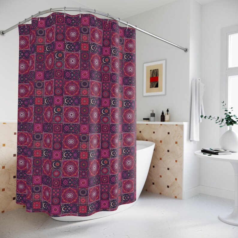 May include: A patterned shower curtain with a repeating design of squares in shades of purple, pink, and red. The squares feature circular and crescent moon motifs. The curtain hangs from a curved metal rod in a bathroom setting.