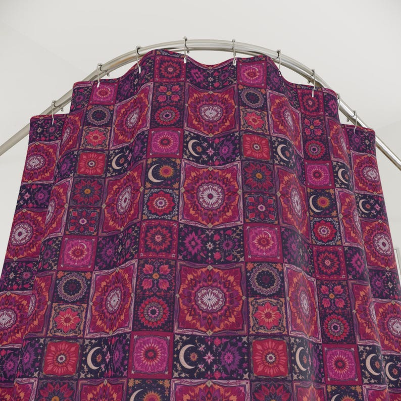May include: A patterned shower curtain with a repeating design of squares in shades of pink, purple, and red. Each square features a floral or geometric pattern, with crescent moon accents. The curtain hangs from a curved metal rod.