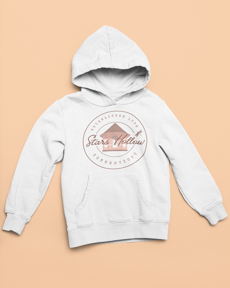 May include: White hoodie with a front pocket and a drawstring hood. The sweatshirt displays a circular graphic with the text "ESTABLISHED 1779 Stars Hollow CONNECTICUT" around a gazebo illustration and a dragonfly.