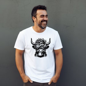 May include: A white t-shirt with a black and white illustration of a Highland cow with its tongue sticking out.