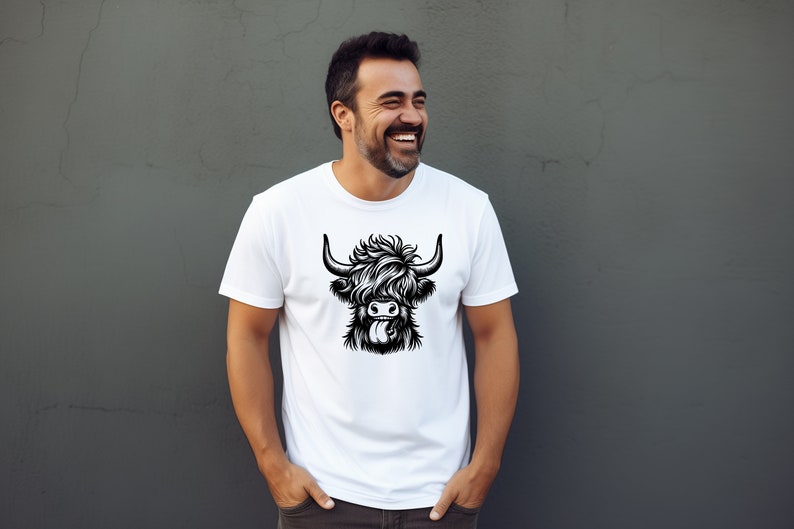 May include: A white t-shirt with a black and white illustration of a Highland cow with its tongue sticking out.