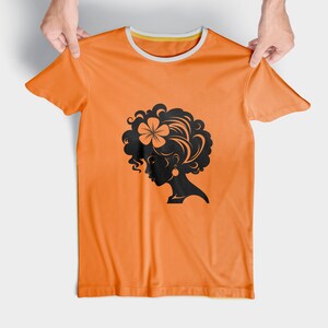 May include: Orange t-shirt with a black silhouette of a woman with curly hair and a flower in her hair.