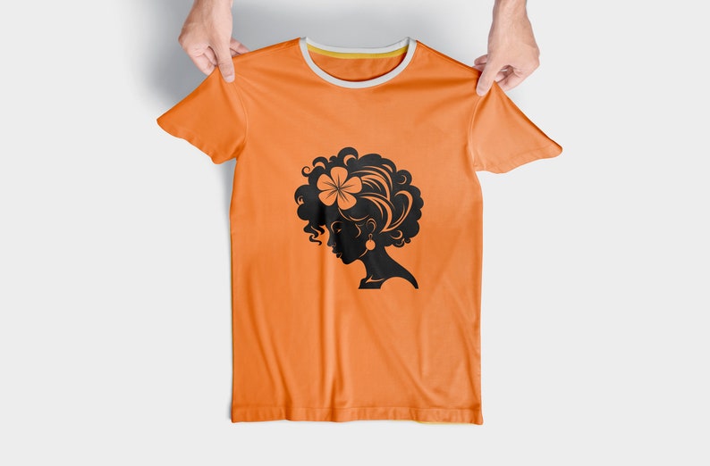 May include: Orange t-shirt with a black silhouette of a woman with curly hair and a flower in her hair.