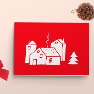 May include: A red card with a white illustration of three houses and a tree. The houses have chimneys and windows. The card is on a light pink background.