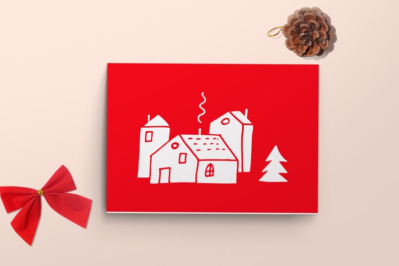 May include: A red card with a white illustration of three houses and a tree. The houses have chimneys and windows. The card is on a light pink background.