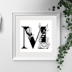May include: A black and white printable art print featuring the letter M with floral embellishments. The letter is in a bold, serif font and is surrounded by stylized leaves and flowers.