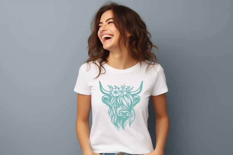 May include: A white t-shirt with a teal floral design of a Highland cow's head.