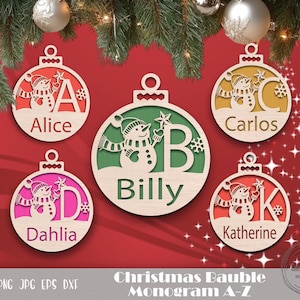 May include: Five wooden Christmas ornaments with a snowman design and a letter of the alphabet. The ornaments are painted in various colors, including pink, green, and brown. The ornaments are labeled with the names Alice, Dahlia, Billy, Carlos, and Katherine.