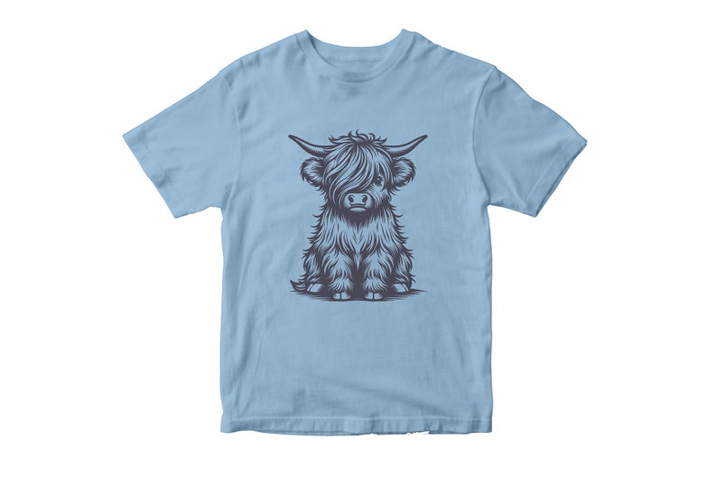May include: A light blue t-shirt with a graphic of a cute, cartoon Highland cow with black fur. The cow is sitting down with its legs crossed.