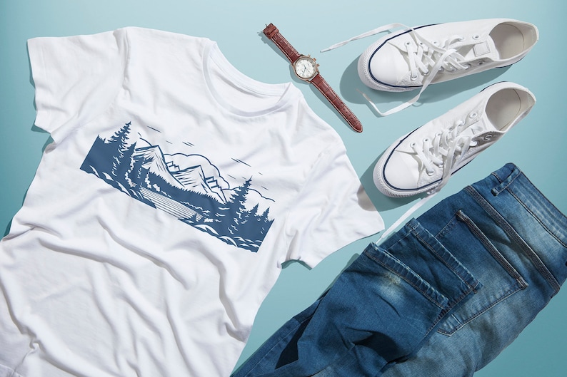 以下が含まれることがあります： 青い山岳風景のグラフィックがプリントされた白いTシャツ、白いスニーカー、茶色の革製の腕時計、青いジーンズ