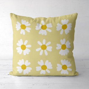 May include: A yellow cushion with a white daisy pattern. The daisies have yellow centres.
