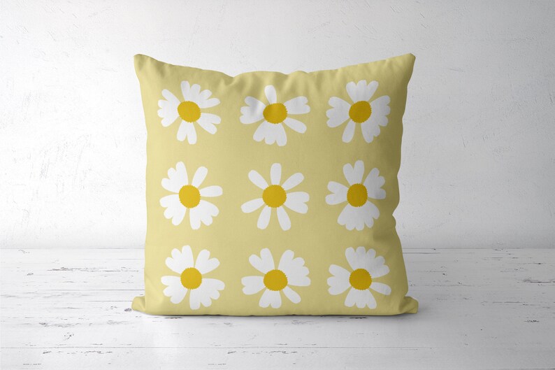 May include: A yellow cushion with a white daisy pattern. The daisies have yellow centres.