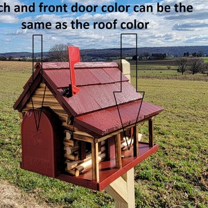 May include: A red wooden mailbox shaped like a log cabin with a porch and a flag on top. The mailbox is mounted on a wooden post. The text "US MAIL" is visible on the front of the mailbox.
