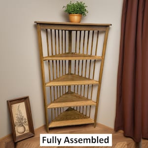 May include: A wooden corner shelf with four triangular shelves and vertical supports. A small potted plant sits on top. A framed picture leans against the shelf. The text "Fully Assembled" is at the bottom.