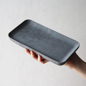 以下が含まれることがあります： コンクリート製の四角い灰色のトレイ。トレイは滑らかで、わずかにざらざらした表面をしています。